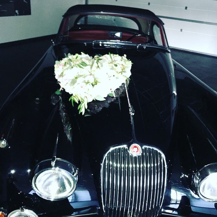 Hochzeitsauto mit weißem Herzgesteck auf der Motorhaube